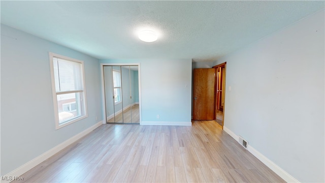 unfurnished room featuring a textured ceiling and light wood-type flooring