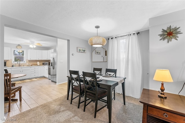 dining space featuring sink, a textured ceiling, and ceiling fan