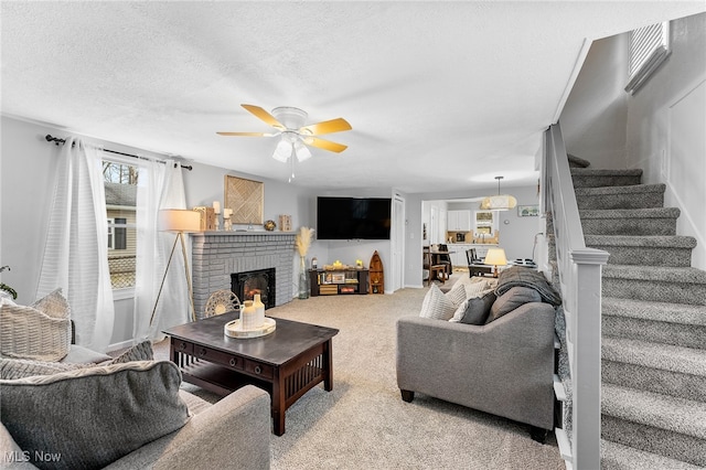 carpeted living room featuring a fireplace, a textured ceiling, and ceiling fan