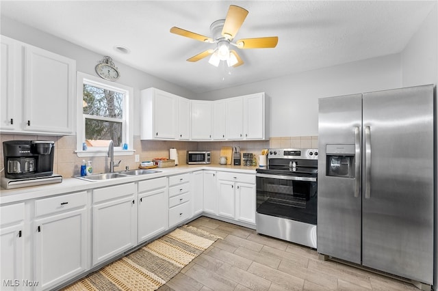 kitchen with sink, appliances with stainless steel finishes, white cabinets, and ceiling fan