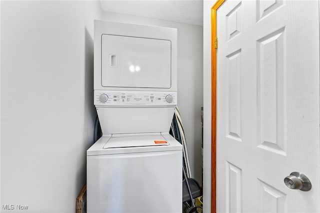 laundry area with stacked washer / dryer and a textured ceiling