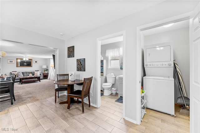 dining area featuring light carpet, stacked washer and dryer, and ceiling fan