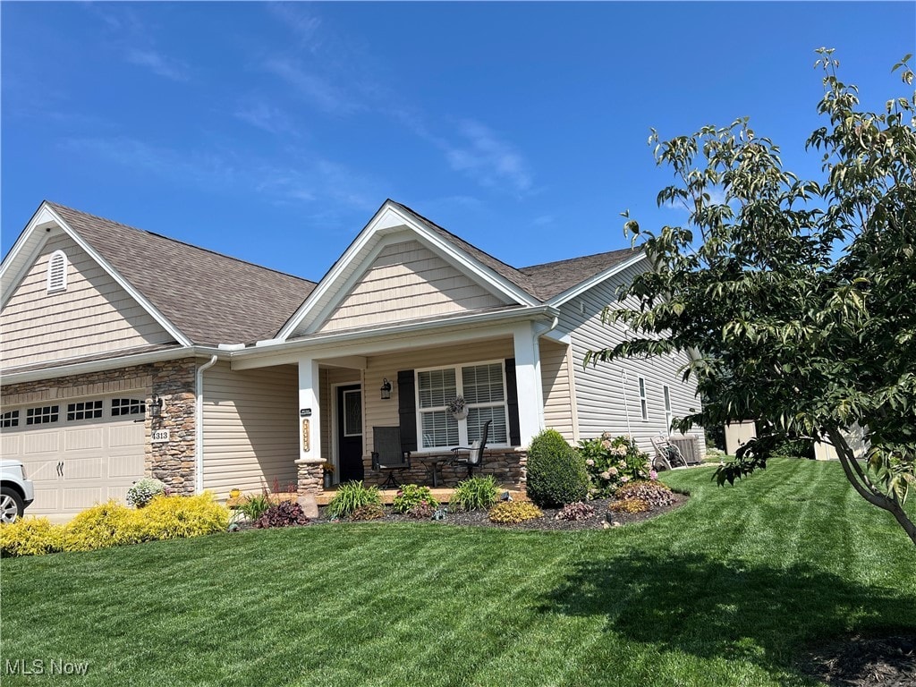 view of front of home featuring a front yard, a porch, and a garage