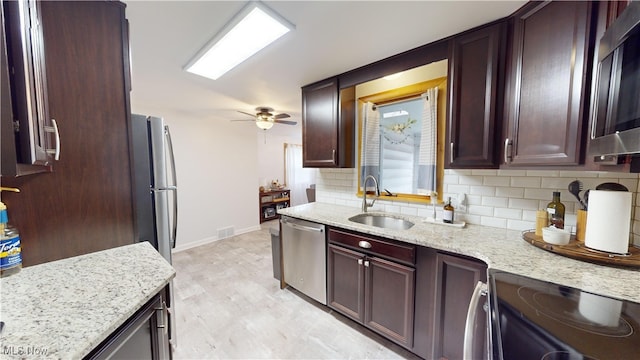 kitchen with light stone counters, stainless steel appliances, decorative backsplash, and sink