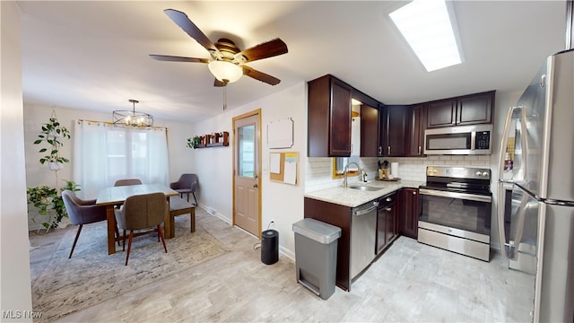 kitchen featuring dark brown cabinets, sink, decorative light fixtures, appliances with stainless steel finishes, and tasteful backsplash