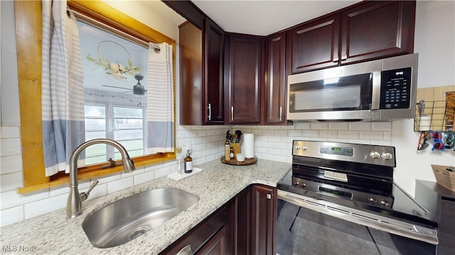 kitchen featuring sink, light stone counters, stainless steel appliances, and tasteful backsplash