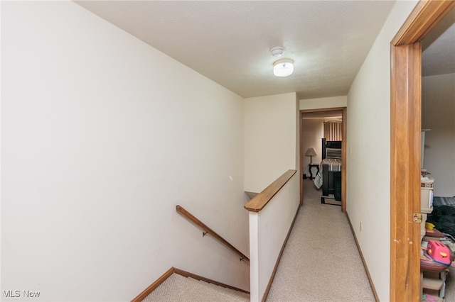 hall featuring light carpet and a textured ceiling