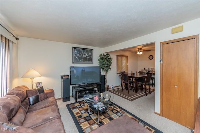 living room featuring a textured ceiling, carpet floors, and ceiling fan