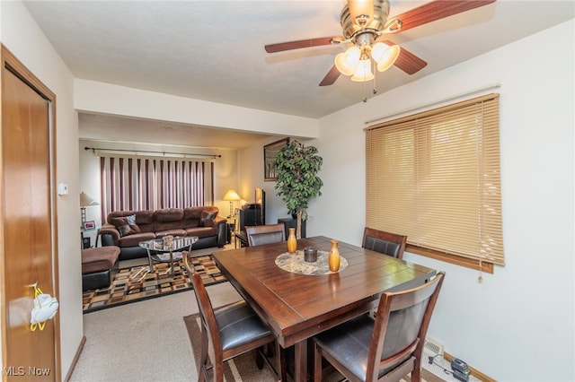 carpeted dining room with a textured ceiling and ceiling fan