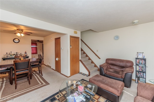 living room with ceiling fan, carpet flooring, and a textured ceiling