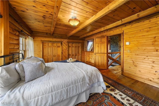 bedroom with wooden walls, wood-type flooring, beam ceiling, wooden ceiling, and a closet