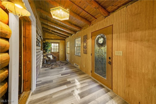 interior space with baseboard heating, wooden walls, wood-type flooring, lofted ceiling with beams, and wooden ceiling