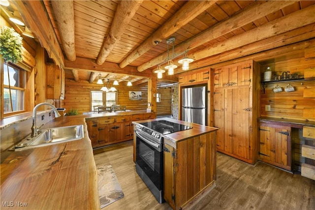 kitchen with hanging light fixtures, wooden walls, sink, appliances with stainless steel finishes, and dark hardwood / wood-style flooring