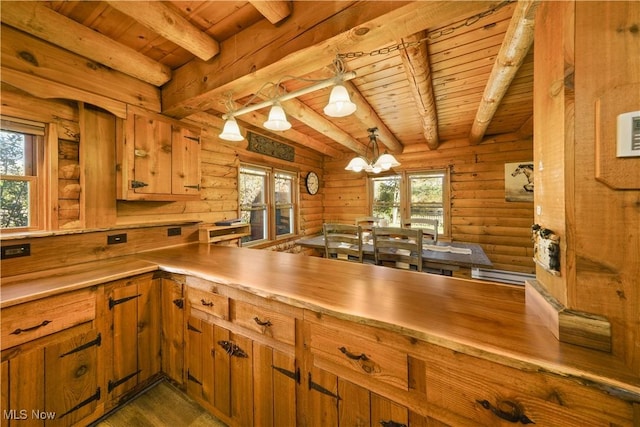 kitchen featuring a wealth of natural light, beamed ceiling, pendant lighting, and an inviting chandelier