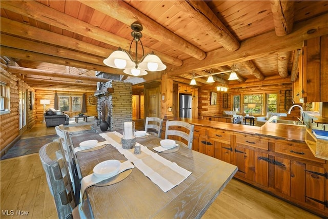 dining room with a healthy amount of sunlight, light wood-type flooring, beam ceiling, and an inviting chandelier