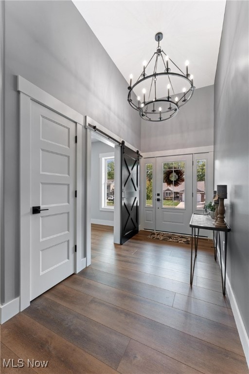 entryway with a healthy amount of sunlight, a towering ceiling, dark hardwood / wood-style flooring, and a barn door