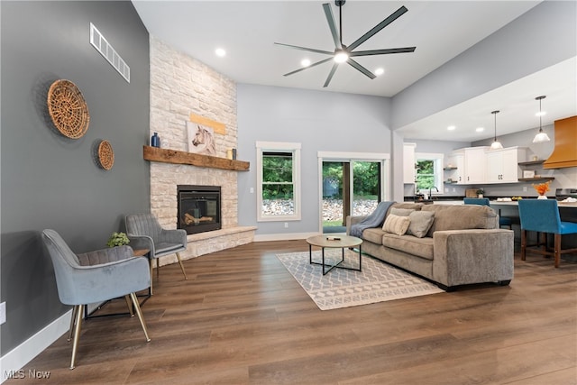 living room featuring a fireplace, dark hardwood / wood-style floors, a towering ceiling, and ceiling fan