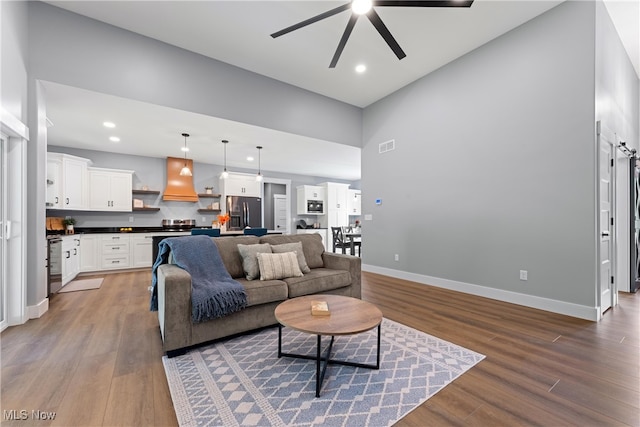 living room with dark wood-type flooring, a high ceiling, and ceiling fan