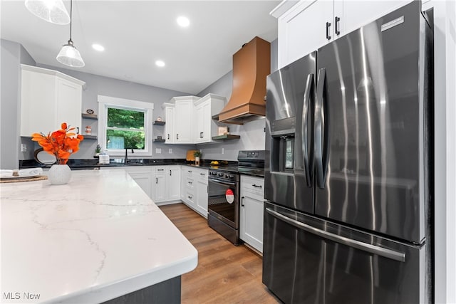 kitchen with stainless steel refrigerator with ice dispenser, decorative light fixtures, black range, white cabinets, and light hardwood / wood-style floors