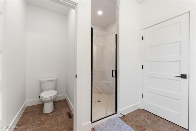 bathroom featuring toilet and a shower with shower door