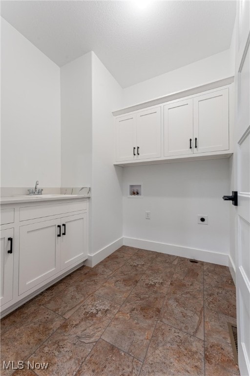 laundry area with hookup for an electric dryer, sink, hookup for a washing machine, and cabinets