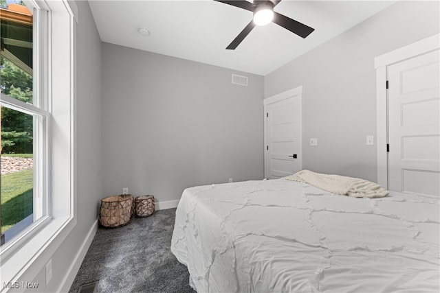 bedroom with dark carpet, multiple windows, and ceiling fan