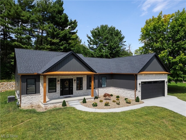 view of front of home featuring covered porch, cooling unit, a garage, and a front lawn