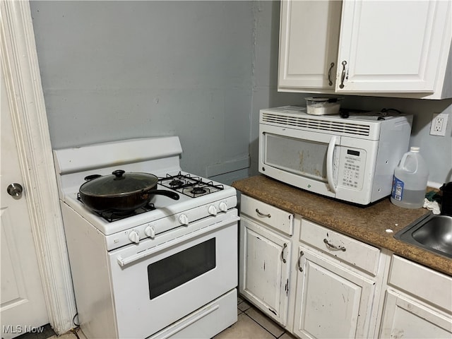 kitchen with white cabinets, sink, light tile patterned floors, and white appliances