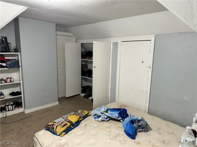 carpeted bedroom featuring a textured ceiling and vaulted ceiling