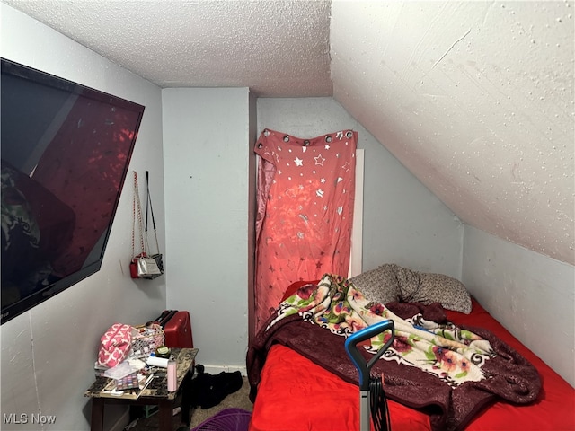 bedroom featuring a textured ceiling and vaulted ceiling