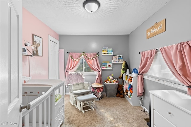 bedroom featuring a textured ceiling, light colored carpet, and a crib