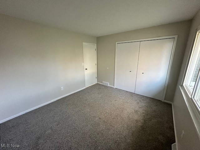 unfurnished bedroom featuring a closet and dark colored carpet