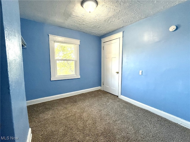 spare room featuring a textured ceiling and carpet flooring