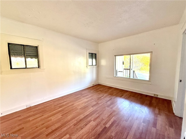 empty room with a textured ceiling and wood-type flooring