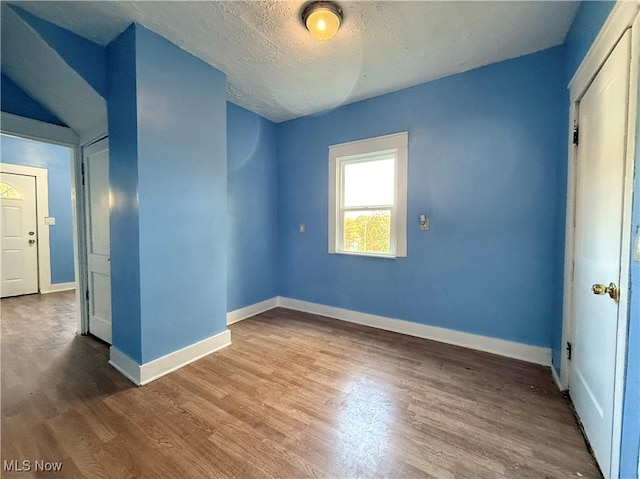 unfurnished bedroom featuring baseboards, a textured ceiling, and wood finished floors