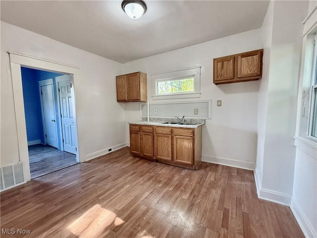 kitchen with brown cabinetry, baseboards, wood finished floors, and visible vents
