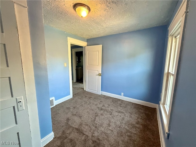 empty room featuring carpet and a textured ceiling