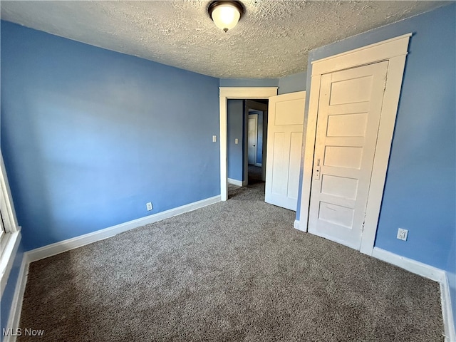 unfurnished bedroom with a textured ceiling and dark colored carpet