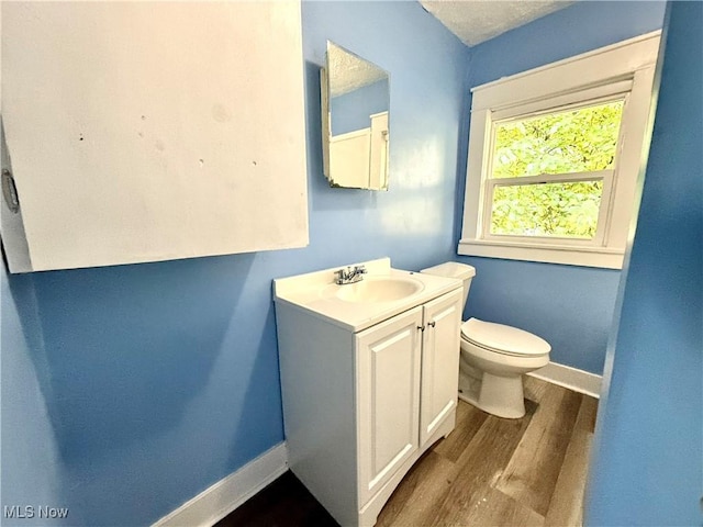 bathroom with baseboards, vanity, toilet, and wood finished floors