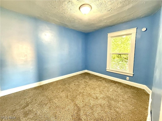 carpeted empty room featuring a textured ceiling and baseboards