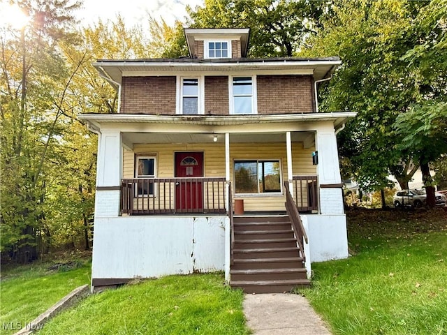 traditional style home featuring a front yard, a porch, stairway, and brick siding