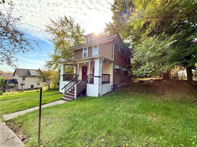 traditional style home featuring a porch, brick siding, and a front yard