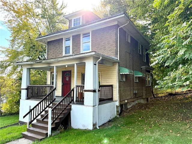 traditional style home featuring a porch, brick siding, and a front yard