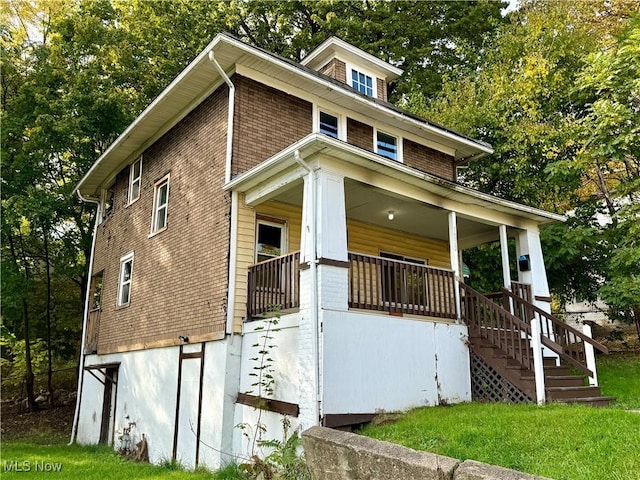 traditional style home with stairway, a front yard, and a porch