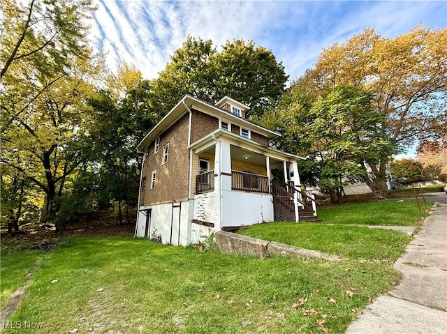 view of side of property featuring covered porch and a lawn