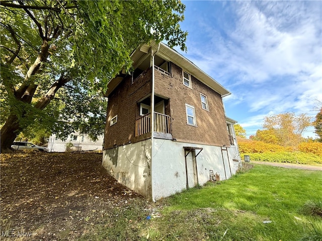 view of property exterior with a balcony and a lawn