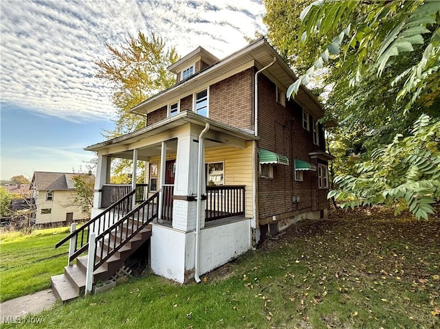 traditional style home featuring brick siding, a front lawn, and covered porch