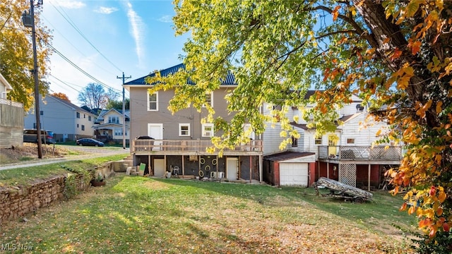 back of house with a deck, a yard, and a garage