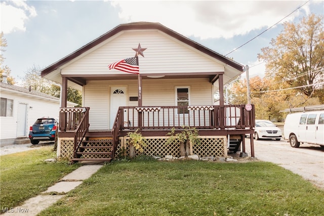 bungalow-style home with a front lawn and a wooden deck