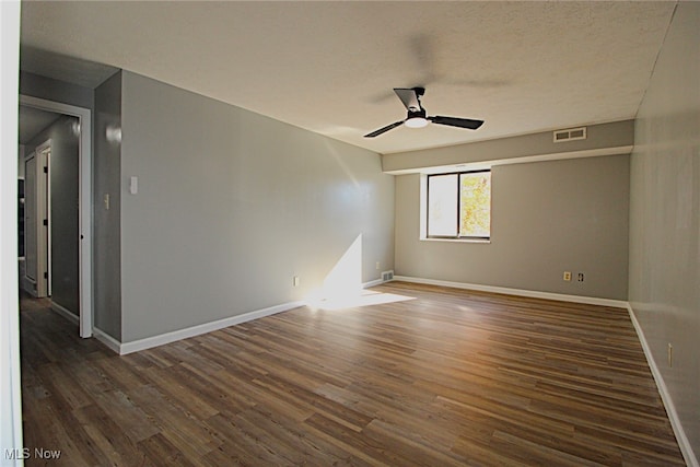 spare room featuring dark wood-type flooring, a textured ceiling, and ceiling fan